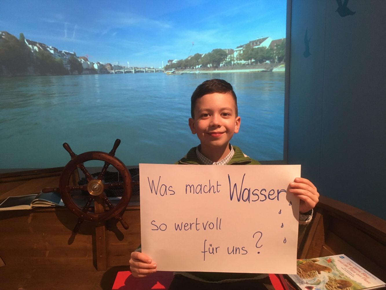 Junge mit Plakat "Was macht Wasser so wertvoll für uns?"